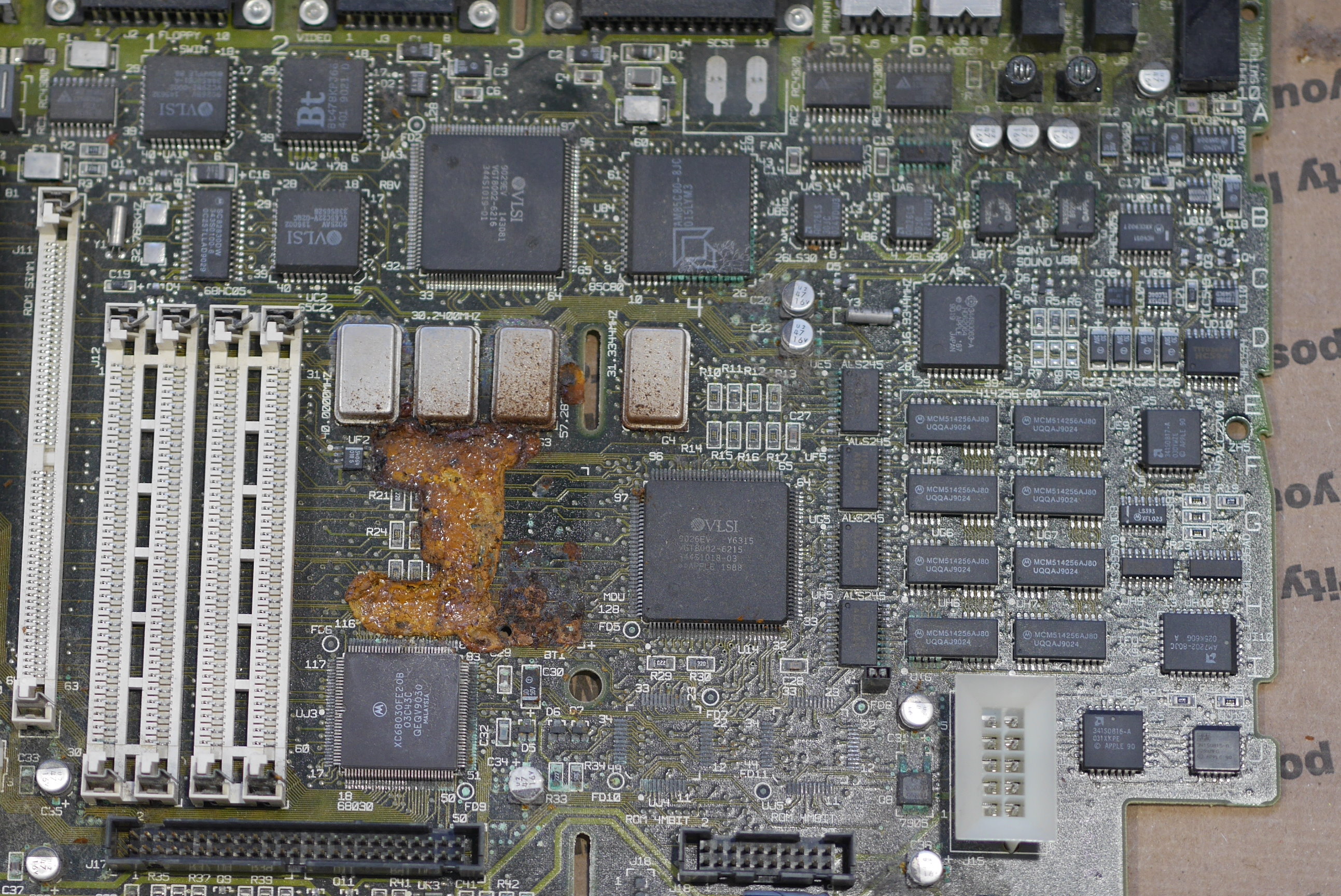 The aftermath of an exploded Maxell battery on a Macintosh IIsi motherboard. The battery itself is nowhere to be found, as it fell off the board due to the corrosion. mac iisi board with battery damage